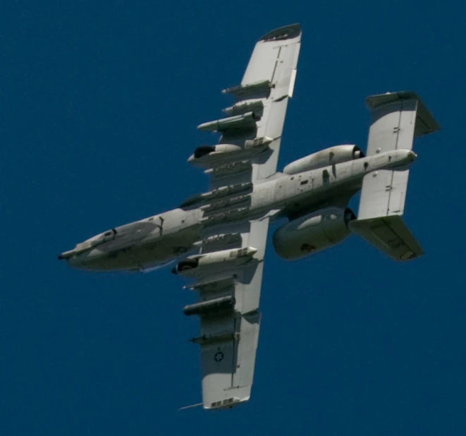 a military jet flying in a clear blue sky