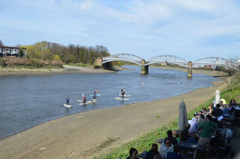 a crowd of people watching a man canoe on the water