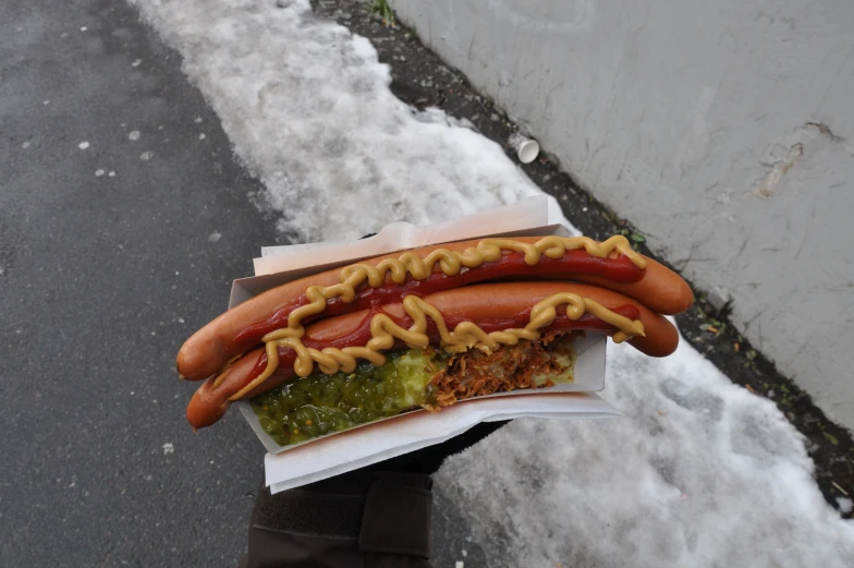  dogs and other condiments in napkins on top of snow