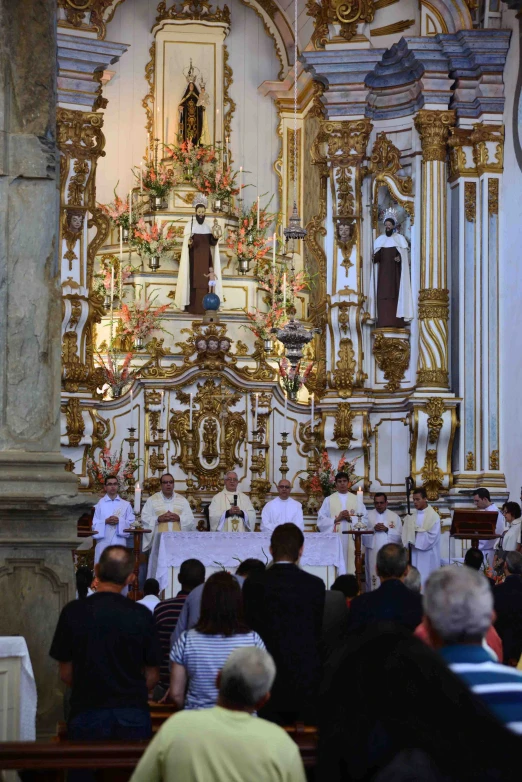 a large group of people sit in front of a priest