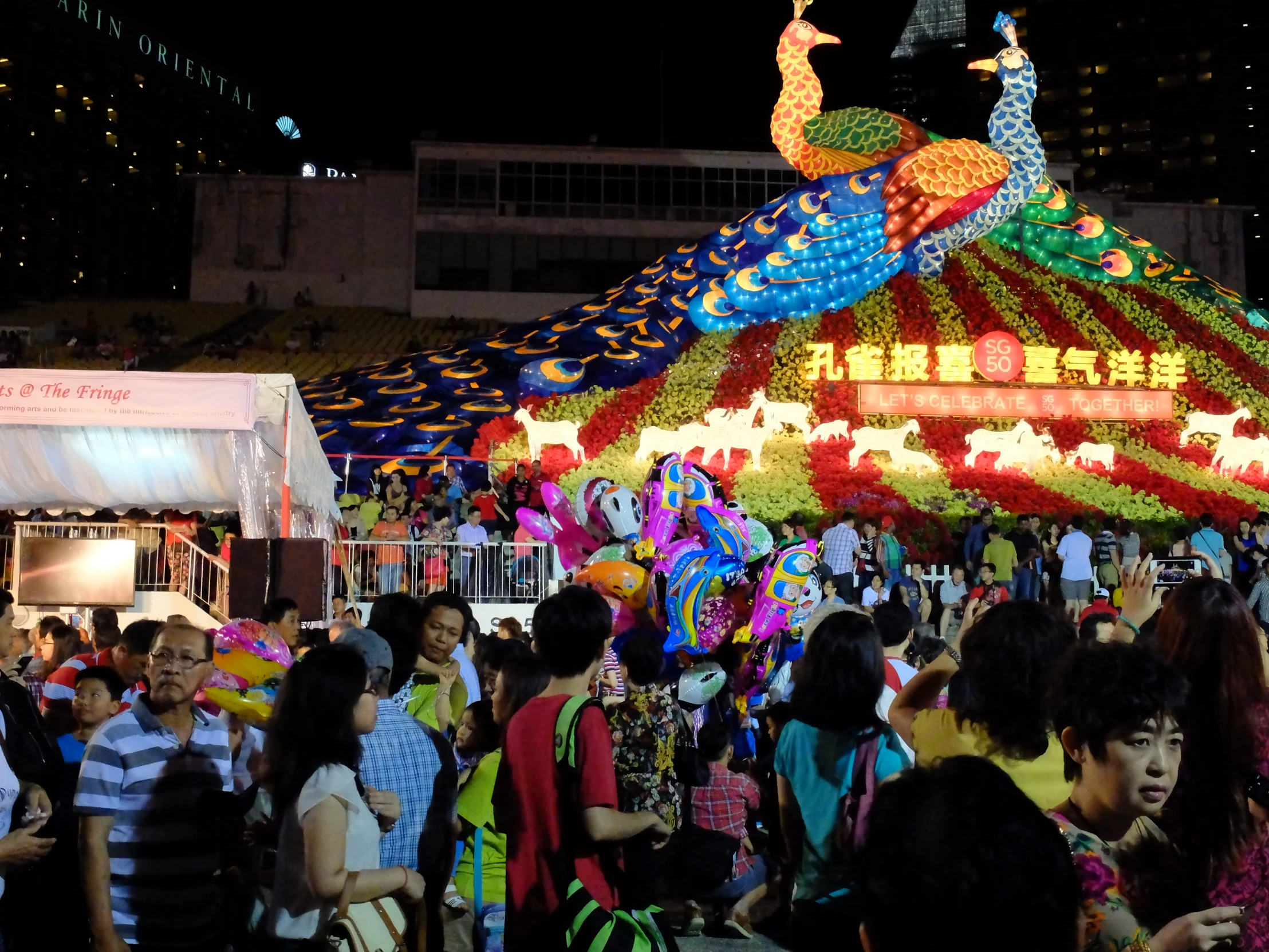 crowds at a parade with floats and lights on