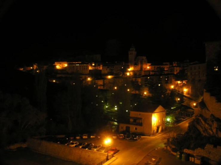 the night view shows a street and a city with buildings in the background