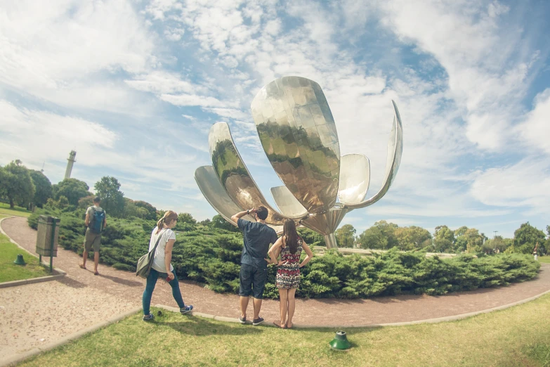 a group of people standing next to a giant piece of art