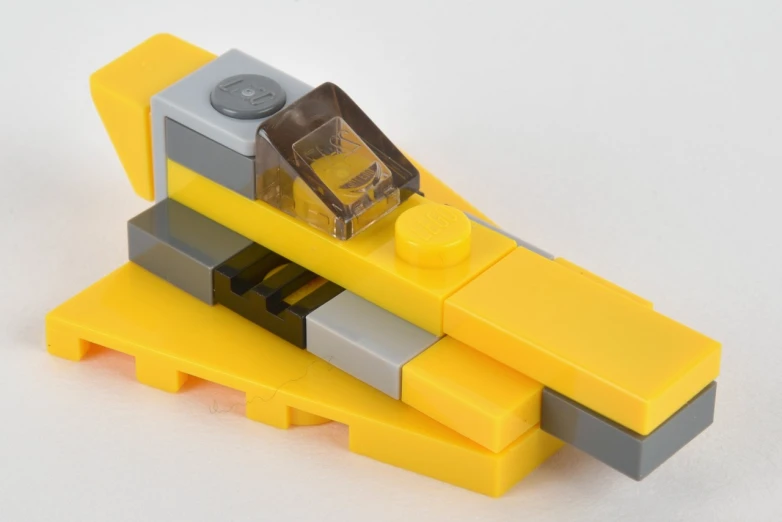 a toy yellow boat with grey and yellow pieces on top