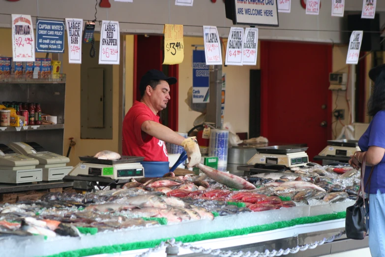 a man is standing behind a buffet in a fish market