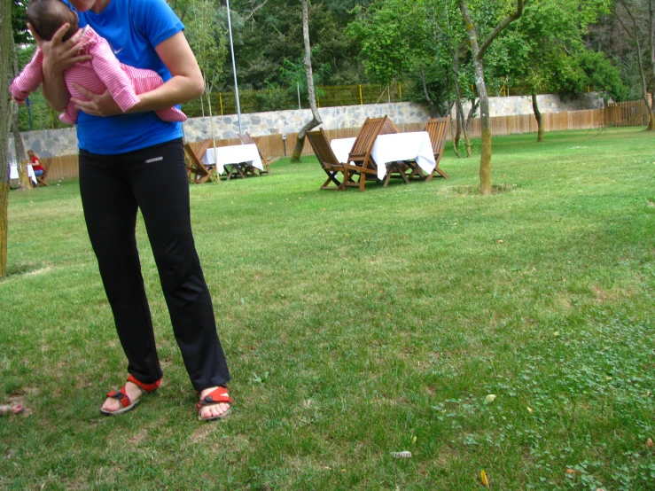 an adult and young child stand in the grass by the picnic area