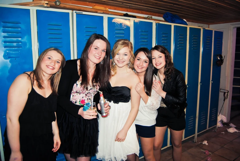 several girls posing for a po in front of some lockers