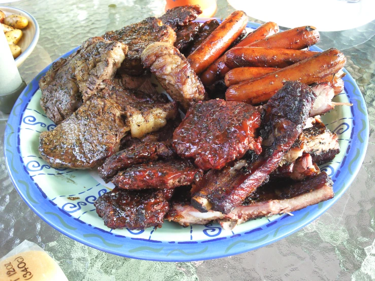 a white and blue plate filled with meat, carrots and meat