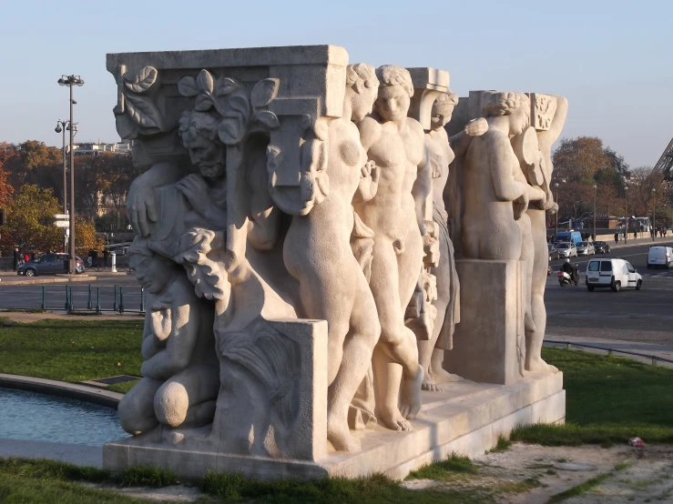 a large white fountain surrounded by statues on the grass