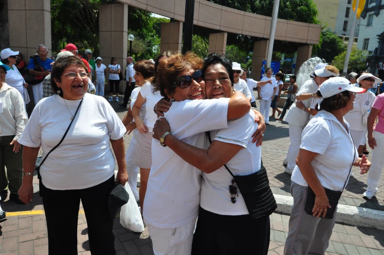 a group of women in white hugging each other