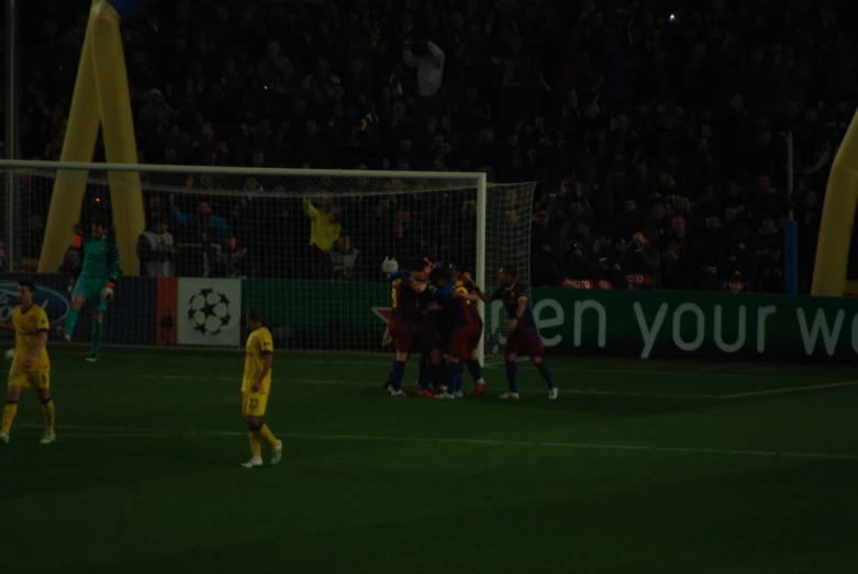 soccer players standing around while a crowd watches