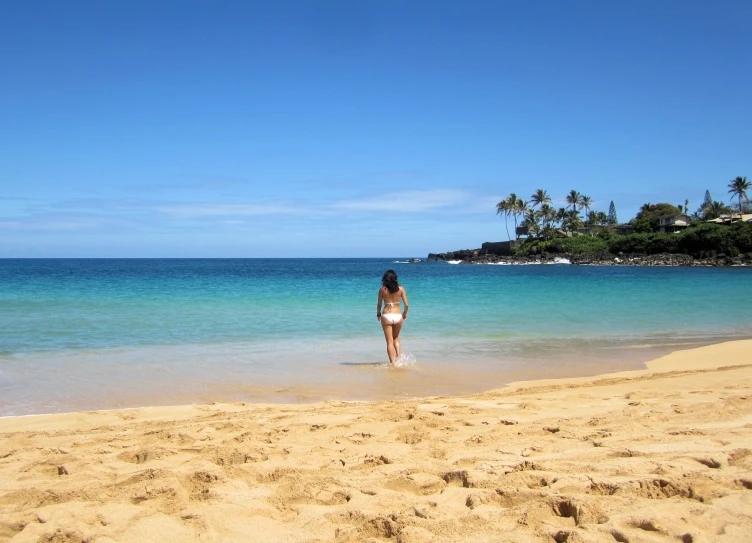 a woman walking out of the ocean with some blue water