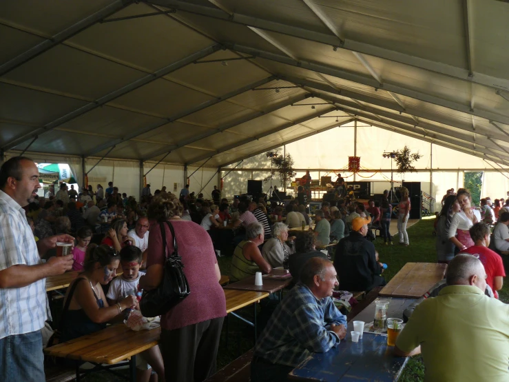 a group of people in a tent sitting at picnic tables