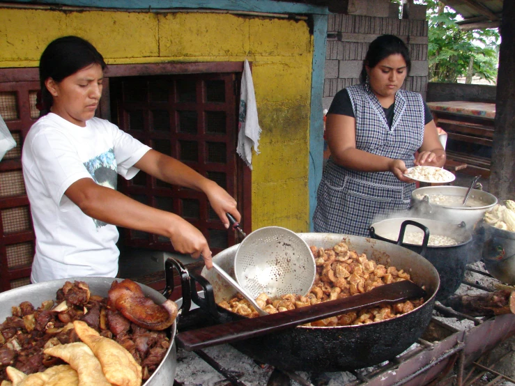 people preparing food on a grill near other dishes