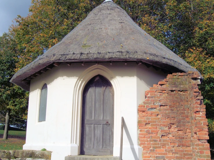 the old brick and stone church has a thatched roof