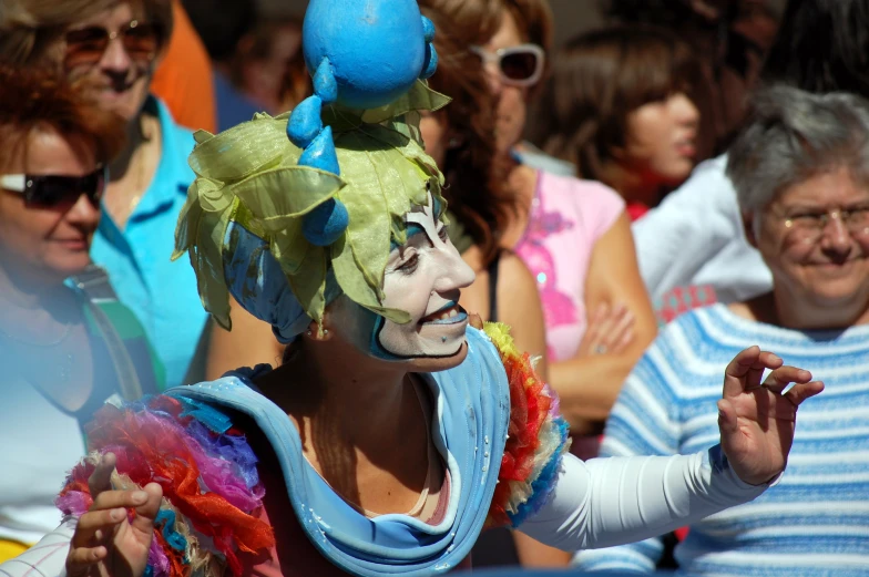 a woman in costume and makeup gestures as others stand around