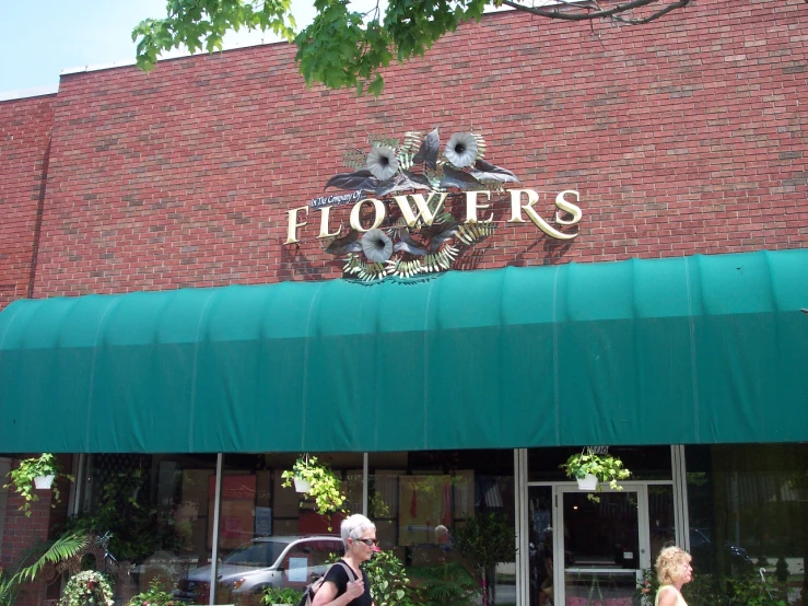 two women walking past a store with flowers in the windows