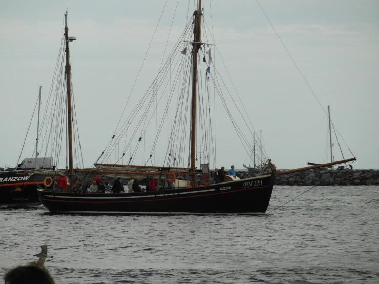 a large sail boat on the water with people looking on