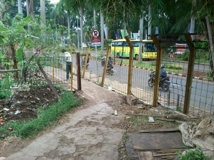 a motorcycle riding by a park with a fence