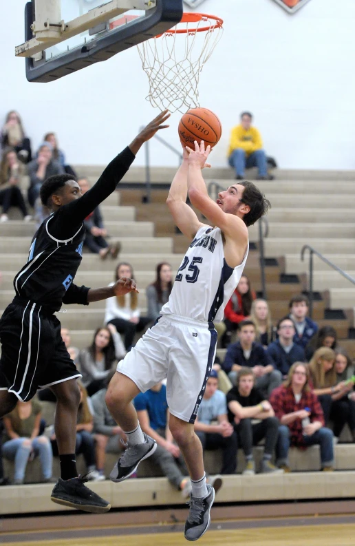 two men in uniforms trying to block a basketball