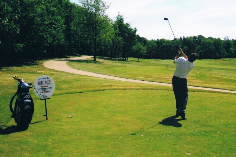 a golf player swings his club on the putting green