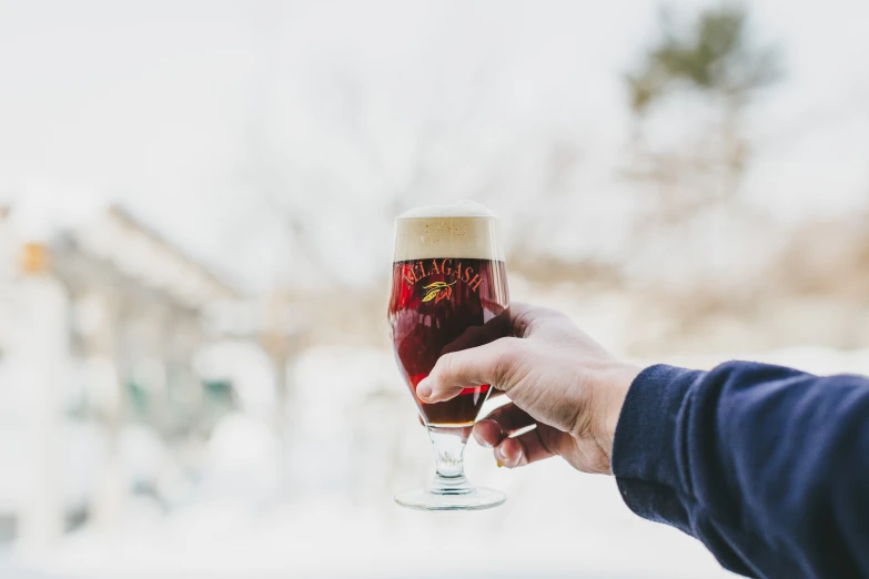 a person holding up a glass in the middle of winter