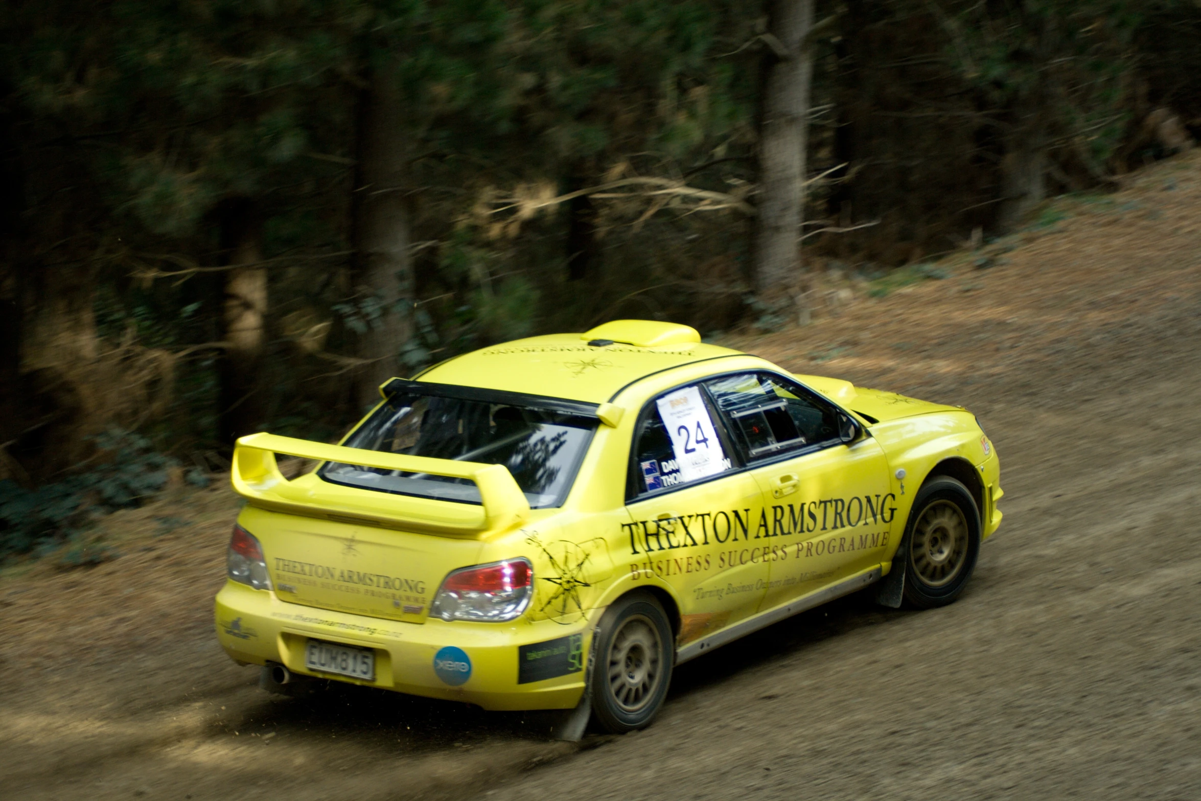 there is a yellow car racing down the dirt road