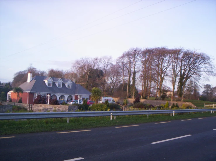 house on the side of a road with trees in the background