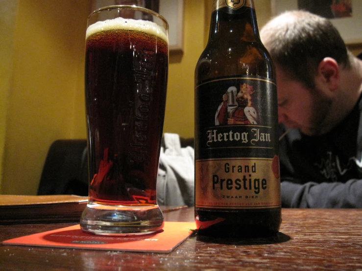 a man looks at a glass full of beer on the table