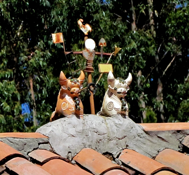 two sculptures on top of a roof near trees