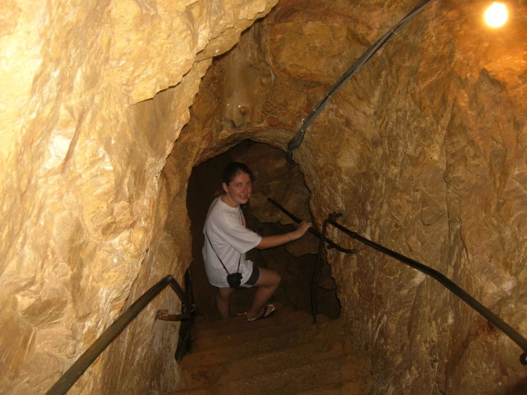 a woman is sitting down in a small tunnel