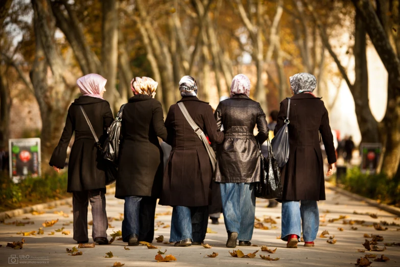 people walking down the street with leaves on the ground