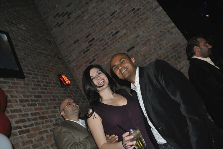 two people posing for a po with a brick wall behind them