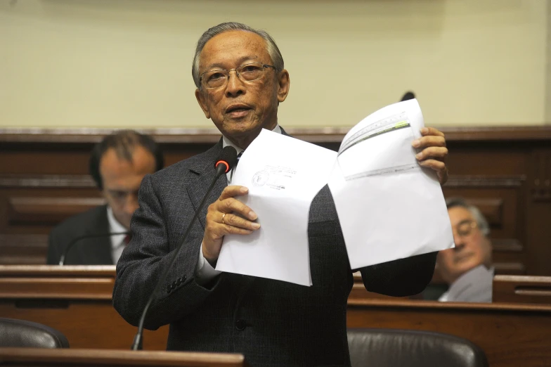 a man holds papers as he holds them in a courtroom