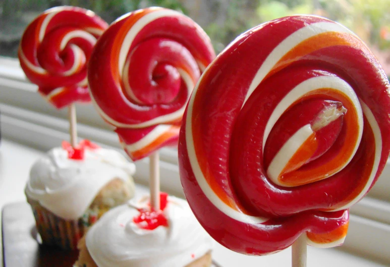 several red lollipops on top of each other with white frosting