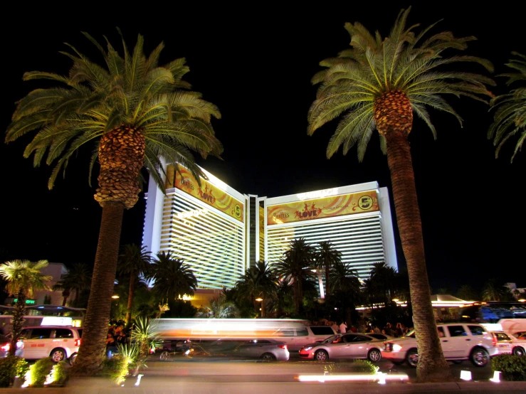 a city scene of some cars parked in front of a large building at night