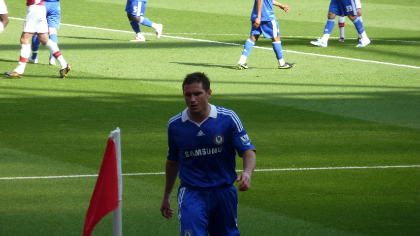 a soccer player wearing blue and white with a flag on a field