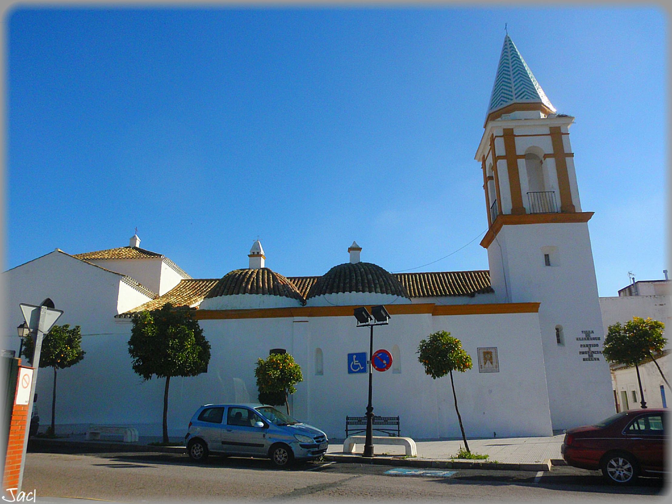 an old church with a steeple and two cars parked outside