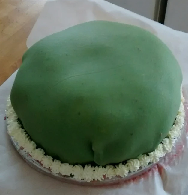 the cake is decorated in green icing and sits on a table