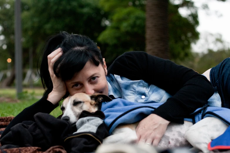 a woman lays in the grass with her dog