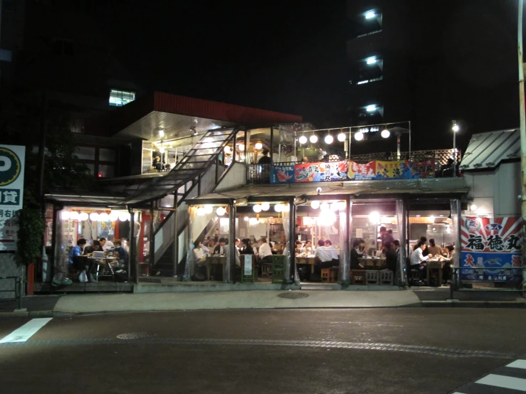 group of people sitting at outdoor dining on the street at night