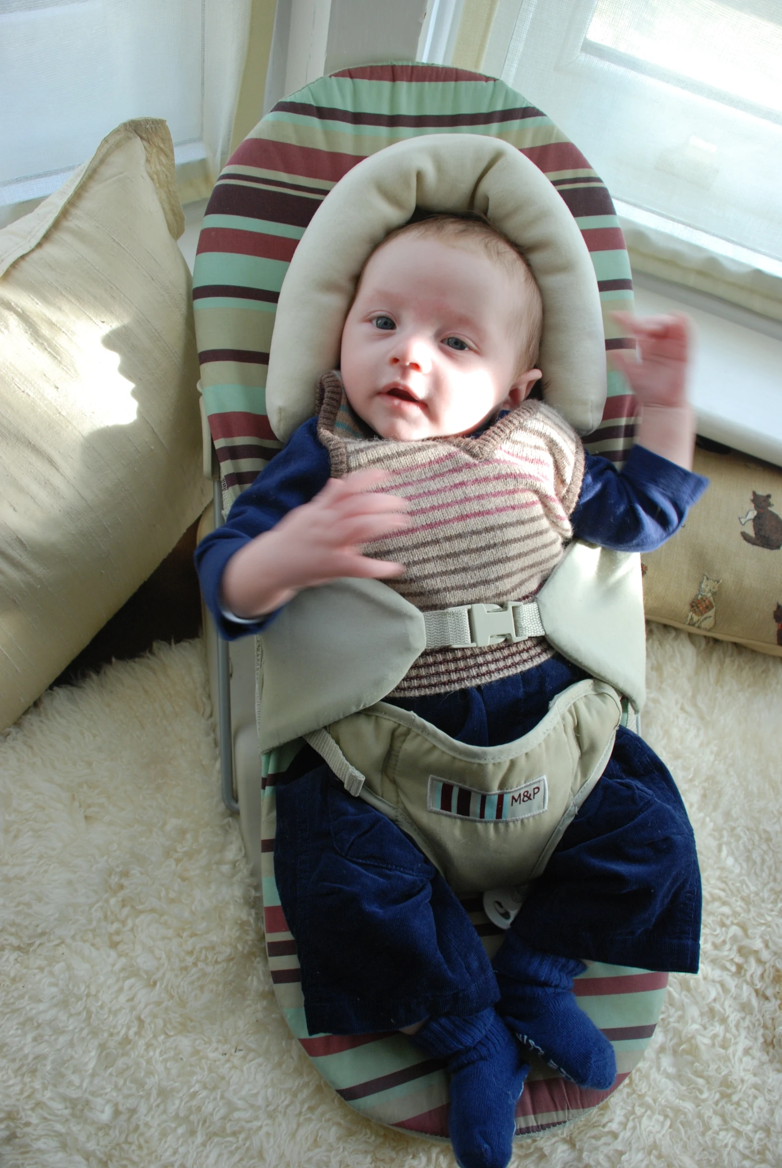 a baby in a carrier sitting on top of a floor