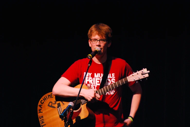 a man playing guitar while standing in front of a microphone