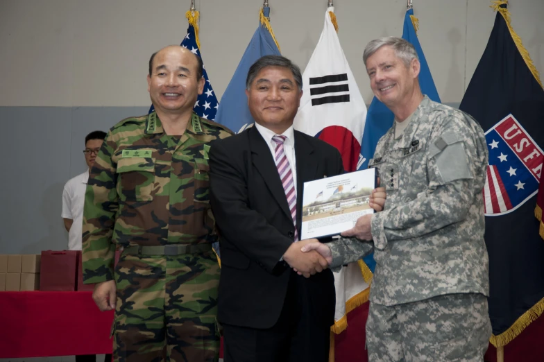 two military officers receiving their awards with a man in uniform