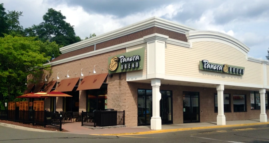 a restaurant with a restaurant name sign next to a tree