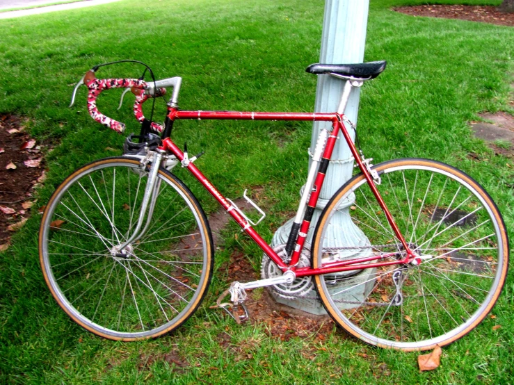 the bicycle is sitting on the ground near the post