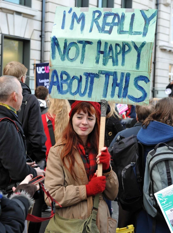 a woman holding a sign in a protest outside a building