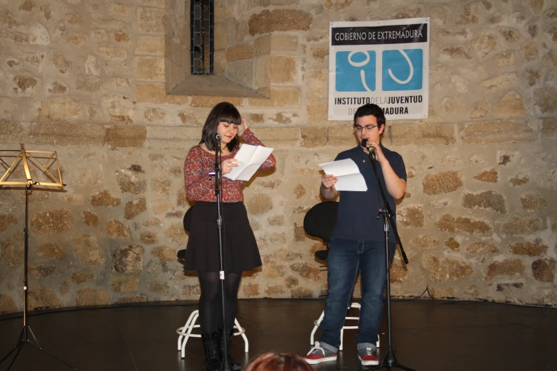 two people on stage with microphones and microphone stand