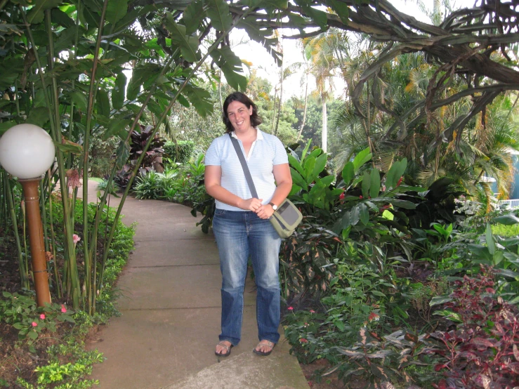 woman standing under tree holding camera at outdoor plant display