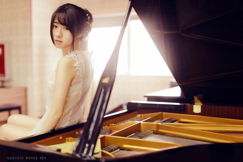 an attractive young lady sitting on a grand piano